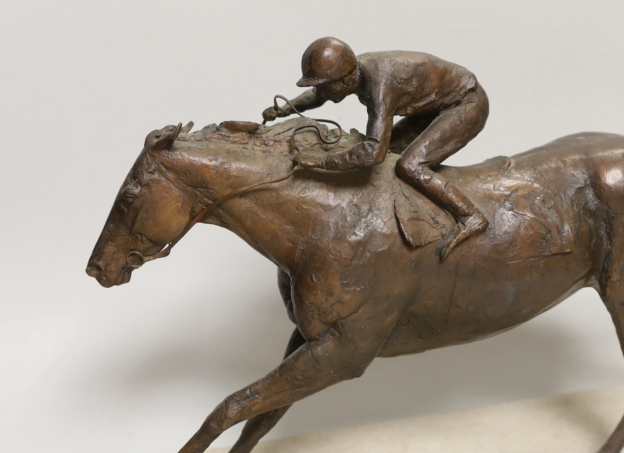 A patinated bronze of a racehorse with jockey, base 48cm long